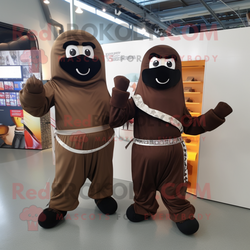 Brown Knife Thrower mascot costume character dressed with a Jumpsuit and Scarves Brown Knife Thrower mascot costume character dressed with a Jumpsuit and Scarves