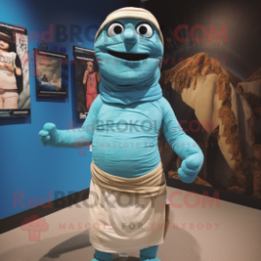 Cyan Mummy mascot costume character dressed with a Board Shorts and Shawl pins