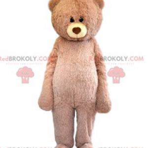 Mascote urso bege muito fofo com seu olhar terno -