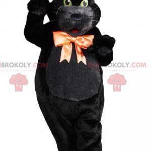 Black cat macsotte with green eyes with its orange bow -