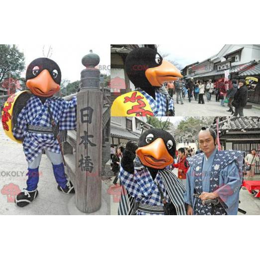 Schwarzes und orange Vogelmaskottchen mit gelbem Schild -
