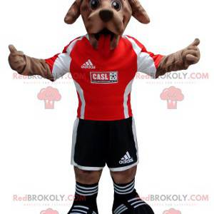 Brązowy pies maskotka w czarno-czerwonym stroju piłkarza -