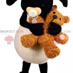 Weißes und schwarzes Schafmaskottchen mit einem Teddybär -