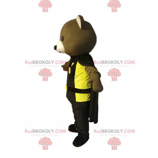 Björnmaskot med en svart cape och en gul t-shirt -