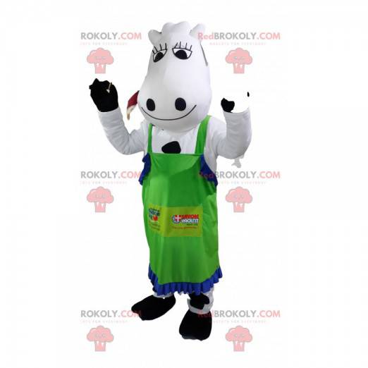 Witte en zwarte koe mascotte met een groen schort. -