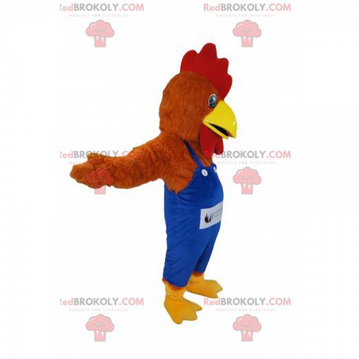 Brązowy kurczak maskotka z niebieskim kombinezonem. -