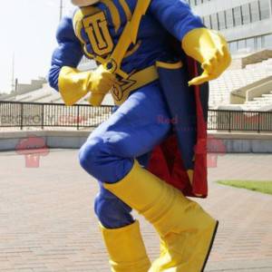 Mascota de superhéroe en traje amarillo y azul con una capa -