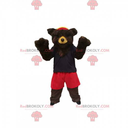 Mascotte d'ours brun avec un short rouge et un maillot marine -