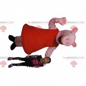 Mascote porco muito sorridente com vestido vermelho -