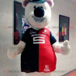 Mascote urso de pelúcia bege com um chapéu e uma camisa -