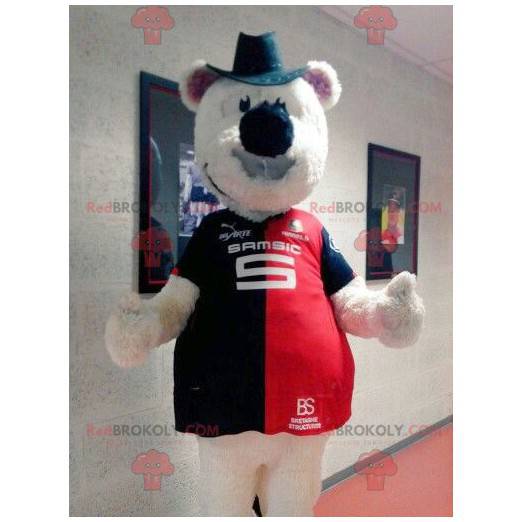Mascote urso de pelúcia bege com um chapéu e uma camisa -