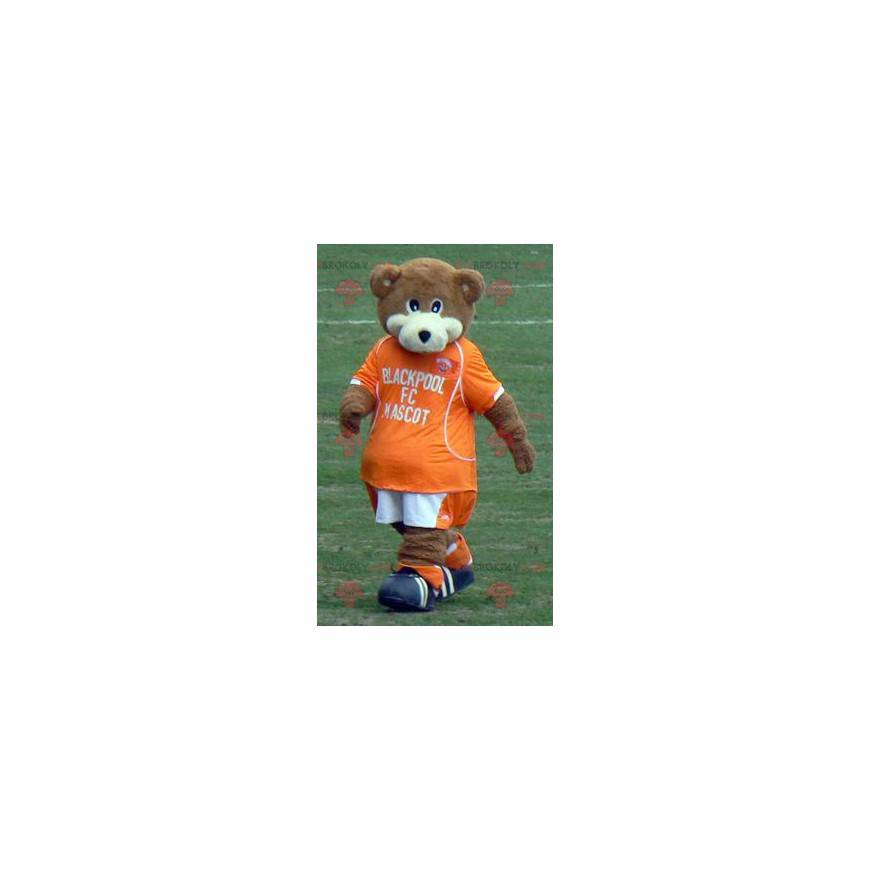 Mascotte de nounours marron et blanc avec une tenue orange -