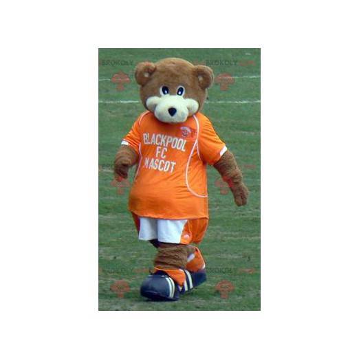 Mascota de oso de peluche marrón y blanco con un traje naranja
