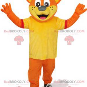 Mascotte orso arancione con una maglietta gialla e un berretto