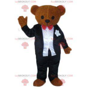 Mascotte de nounours marron habillé d'un costume noir et blanc