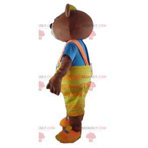 Mascotte orso bruno con tuta gialla e una maglietta -