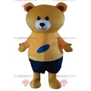 Big beige teddy bear mascot in orange and blue outfit -