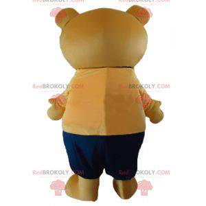 Mascota de oso de peluche beige grande en traje naranja y azul