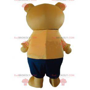 Big beige teddy bear mascot in orange and blue outfit -