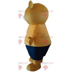 Big beige teddy bear mascot in orange and blue outfit -