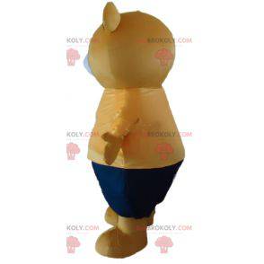 Big beige teddy bear mascot in orange and blue outfit -