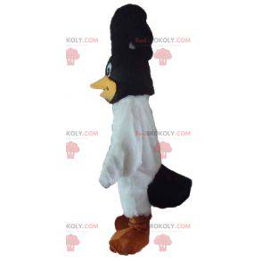 Schwarzweiss-Vogelmaskottchen mit einem Wappen auf dem Kopf -