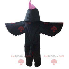 Schwarzes Vogelmaskottchen mit einem rosa Wappen auf dem Kopf -