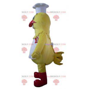 Reusachtige gele kip mascotte gekleed als een chef-kok -