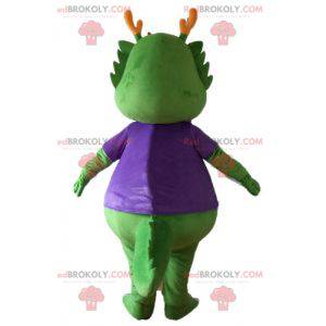 Mascotte groene dinosaurus gekleed in zeer warm paars -