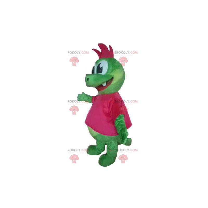 Grünes Dinosaurier-Drachenmaskottchen mit einem rosa Wappen -
