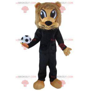 Mascotte de lion marron en tenue de sport noire avec un ballon