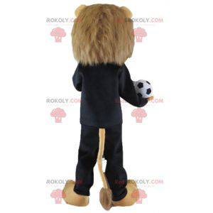 Brun lejonmaskot i svart sportkläder med en boll -