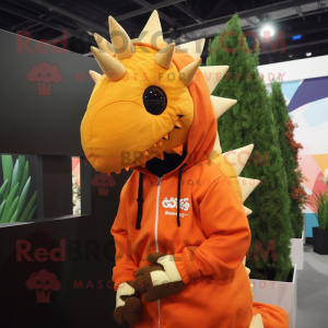 Orange Stegosaurus mascot costume character dressed with a Hoodie and Lapel pins