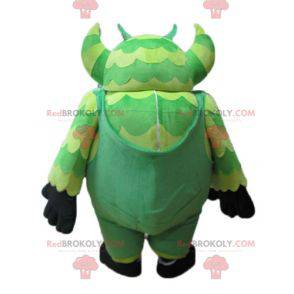 Monstro mascote verde de macacão muito grande e engraçado -