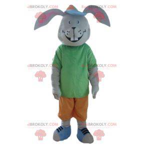 Mascote coelho cinza sorrindo com uma roupa colorida -