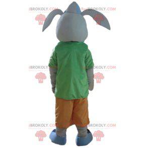 Grijs konijn mascotte lachend met een kleurrijke outfit -