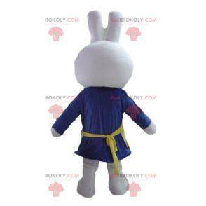Wit konijn mascotte gekleed in blauw met een schort -