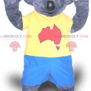 Szara maskotka koala w niebieskim i żółtym stroju -