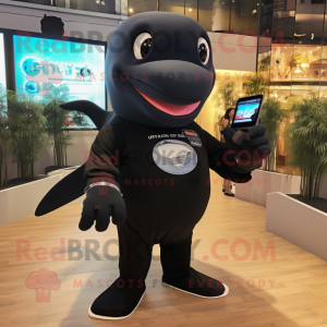 Black Humpback Whale mascot costume character dressed with a T-Shirt and Smartwatches