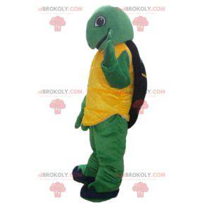 Simpática e sorridente mascote tartaruga amarela verde e preta