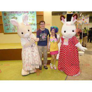 2 mascottes van witte en beige konijnen in kleding -