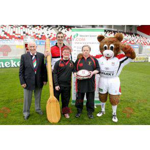 Mascotte de nounours marron et blanc avec une tenue de sport -