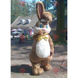 Mascotte de gros lapin marron et blanc avec un nœud de papillon