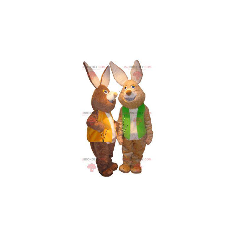 2 maskoti hnědých a bílých králíků s barevnými vestami -
