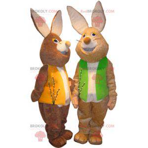 2 mascotes de coelhos marrons e brancos com coletes coloridos -