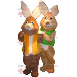 2 mascottes van bruine en witte konijnen met gekleurde vesten -