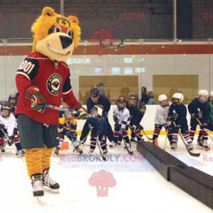 Mascotte dell'orso arancione in attrezzatura da hockey -