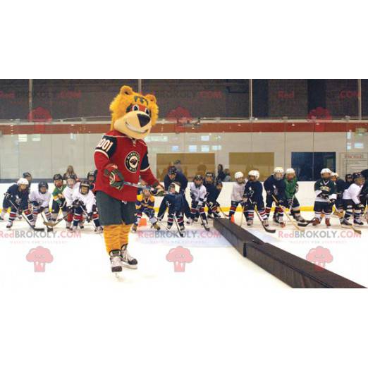 Mascotte dell'orso arancione in attrezzatura da hockey -