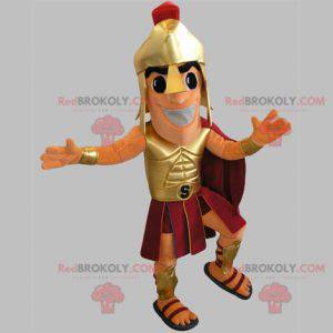 Mascote gladiador em traje dourado e vermelho - Redbrokoly.com