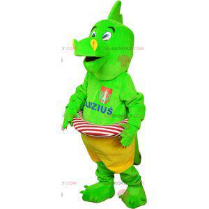 Mascotte di dinosauro verde appariscente in pantaloncini con